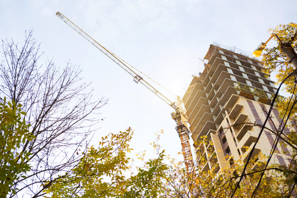 Construction of a multi-storey apartment building in the city. A crane near a skyscraper. Building, moving to a new flat, mortgage, rent and purchase real estate. Copy space